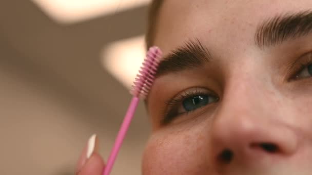 Close-up Porträt kaukasische Frau kämmt ihre Augenbrauen. — Stockvideo