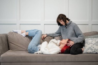 Genç kızlar kanepede yatarken sarılıyorlar. Tek cinsiyetli aşk.