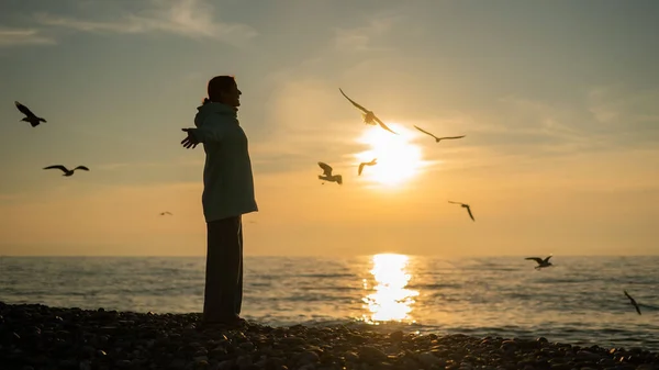 Femme caucasienne écarta ses bras comme des ailes sur le bord de la mer au coucher du soleil. — Photo
