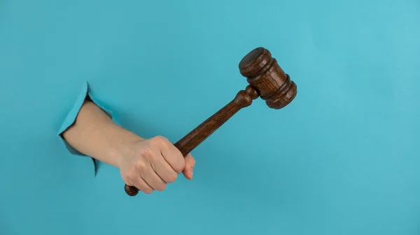 Womans Hand Wooden Judges Gavel Sticks Out Hole Blue Background — Stock Photo, Image