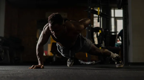 African american man doing one arm push ups in the gym