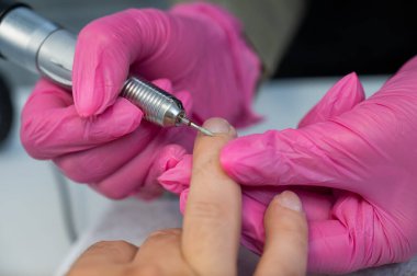 Usta, erkek müşteriye donanım manikürü yapıyor.