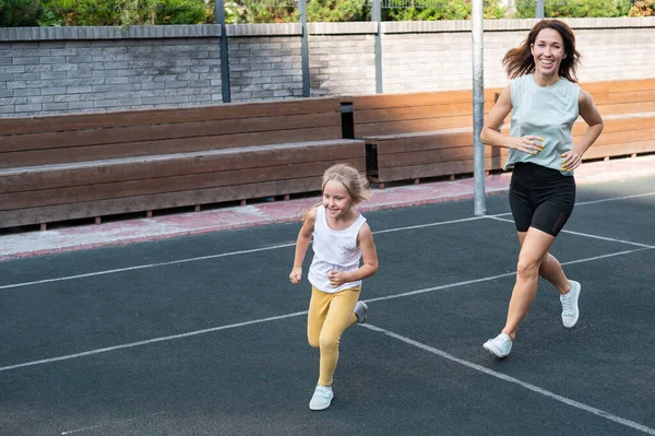 여성은 야외에서 스포츠를 갑니다 여학생 어머니 운동장에서 뛰어다니고 있습니다 — 스톡 사진