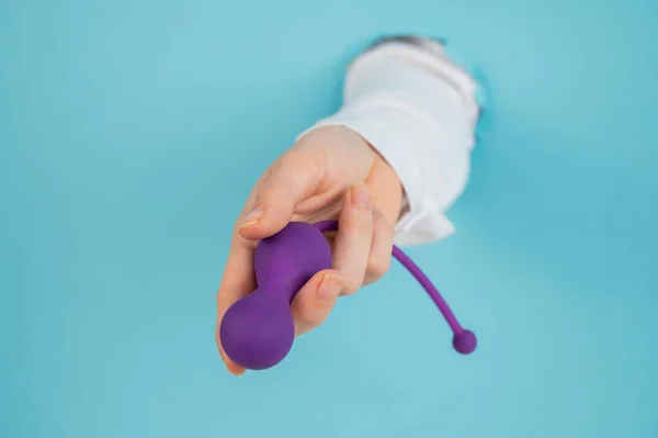 Female Hand Sticking Out Hole Blue Background Holding Kegel Machine — Stock Photo, Image