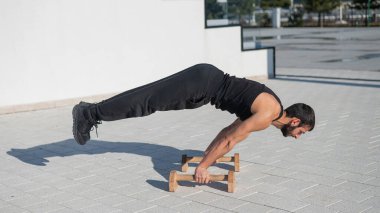 Spor yapmak için zemin parmaklıklarında denge egzersizi yapan adam.