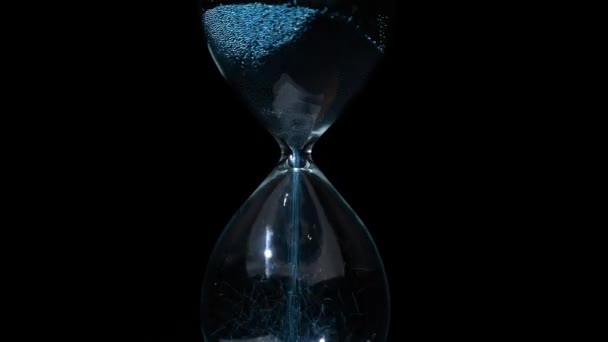 Man Puts Blue Hourglass Spins Black Background — Stock Video