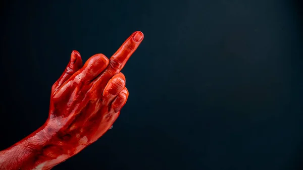 血液で染色された女性の手は黒い背景に中指を示しています — ストック写真