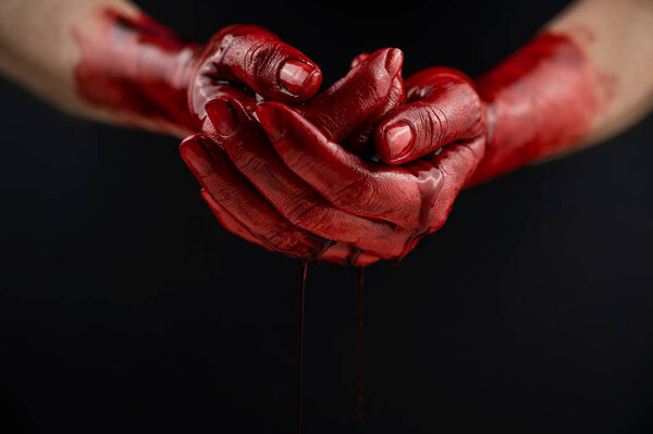 Woman holding blood-stained palms together on black background