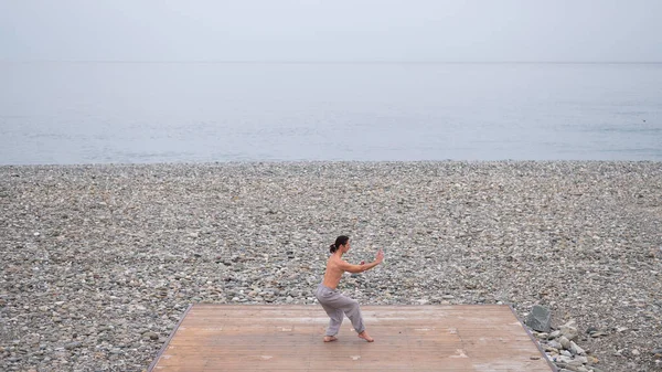 海岸で武術を練習している裸の胴を持つ白人男性 — ストック写真
