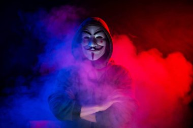 5 Haziran 2022 Novosibirsk, Rusya: Kırmızı-mavi dumanda Anonymous 'un kapüşonlu portresi