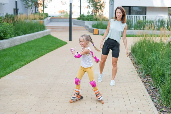 Caucasian woman teaches her daughter to skate on roller skates