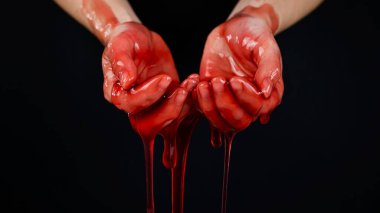 Kadınların elleri kana benzer kırmızı bir sıvının içinde.