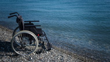 Kayalık bir sahilde boş bir tekerlekli sandalye.