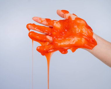 Beyaz arka planda bir kadının elinden akan kırmızı balçık.