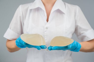 Doktor plastik cerrah farklı göğüs implantları gösteriyor.