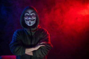 5 Haziran 2022 Novosibirsk, Rusya: Kırmızı-mavi dumanda Anonymous 'un kapüşonlu portresi