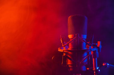 Siyah arka planda pembe dumanlı profesyonel mikrofon.