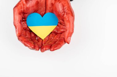 Elleri kana bulanmış bir kadın beyaz arka planda Ukrayna bayrağı taşıyan bir kalp tutuyor.