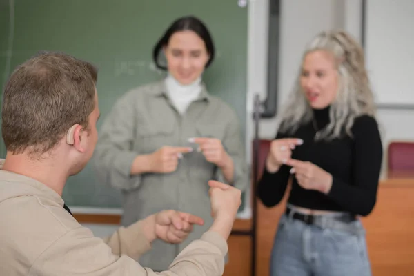 二人の少女と一人の男が手話で話している 3人の聴覚障害者が大学の教室でおしゃべり — ストック写真