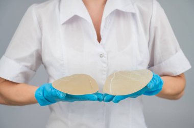 Doktor plastik cerrah farklı göğüs implantları gösteriyor.