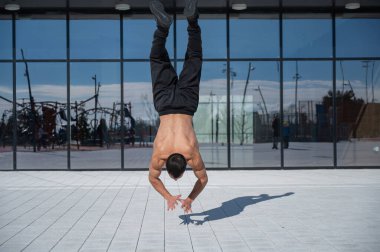 Bir adam panoramik pencerelerin arka planında amuda kalkıyor.