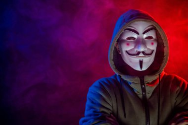 5 Haziran 2022 Novosibirsk, Rusya: Kırmızı-mavi dumanda Anonymous 'un kapüşonlu portresi