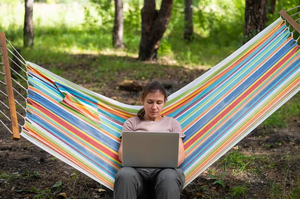 Biała Kobieta Pracująca Laptopie Siedząc Hamaku Lesie Dziewczyna Korzysta Bezprzewodowego — Zdjęcie stockowe