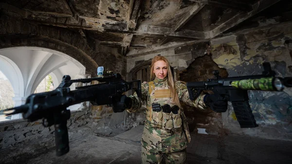 Caucasian woman in army uniform holding two machine guns