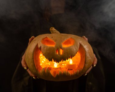 Cadı, karanlıkta parlayan bir fenerle ilgili bir balkabağı krikosu tutuyor. Cadılar Bayramı