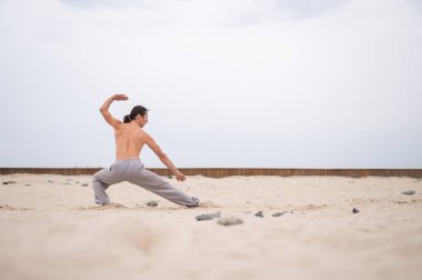 Kafkasyalı, uzun saçlı, dışarıda qigong antrenmanı yapan bir adam.