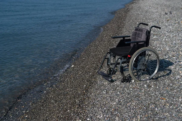 Una Sedia Rotelle Vuota Una Spiaggia Rocciosa — Foto Stock