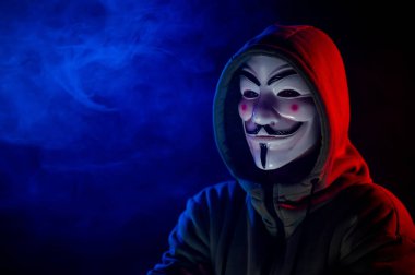 5 Haziran 2022 Novosibirsk, Rusya: Kırmızı-mavi dumanda Anonymous 'un kapüşonlu portresi
