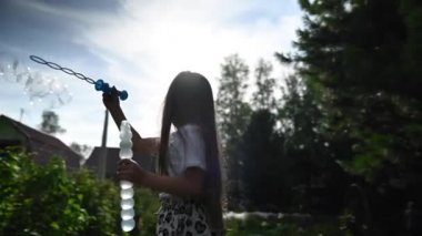 Küçük kız dışarıda sabun köpüğüyle oynuyor. Video 360 derece. Yavaş çekim