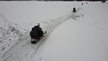 İnsanlar kışın kar motosikletlerine biner.