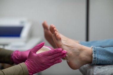 Usta kremi sürüyor ve kadın bir müşterinin ayaklarına masaj yapıyor.