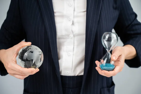 Business woman holding crystal globe and hourglass