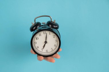 Bir kadın mavi kağıttan bir arka planda bir delikten dışarı çıkar ve çalar saati tutar. Boşluğu kopyala