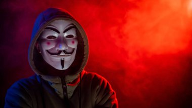 5 Haziran 2022 Novosibirsk, Rusya: Kırmızı-mavi dumanda Anonymous 'un kapüşonlu portresi