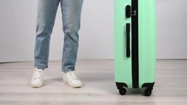 Kadın valizini yere koyar ve yukarıdan atlar. Kız bavulu test ediyor.