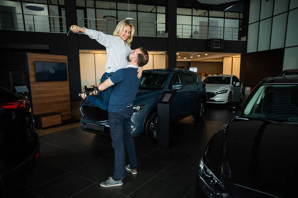 Feliz Casal Caucasiano Abraçando Enquanto Compra Carro Novo Uma Concessionária — Fotografia de Stock