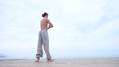 Kafkasyalı, uzun saçlı, dışarıda qigong antrenmanı yapan bir adam.