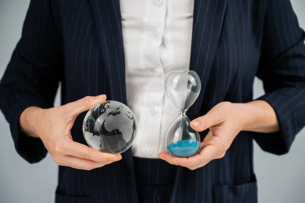 Business woman holding crystal globe and hourglass