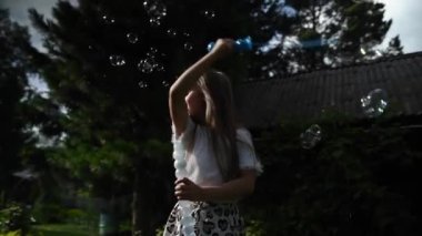 Küçük kız dışarıda sabun köpüğüyle oynuyor. Video 360 derece. Yavaş çekim