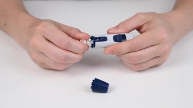 Beyaz bir kadın kalem mızrağı kullanarak glikoz testi yapıyor.