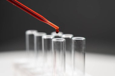 Laboratuvar asistanının, pipetten kan damlatarak test tüpüne kan damlattığı yakın plan.
