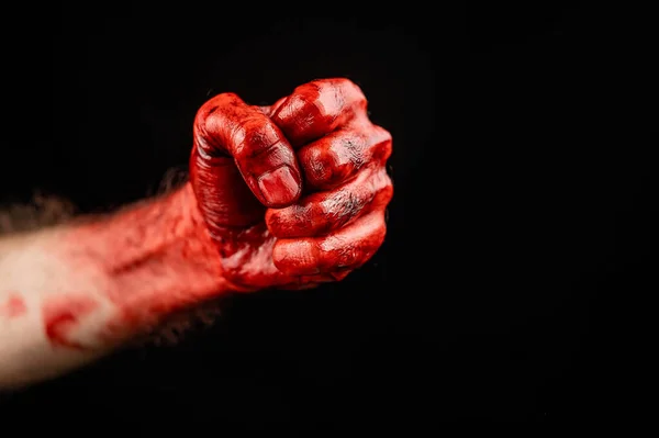 Bloody male fist on a black background. Copy space