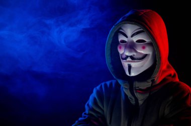 5 Haziran 2022 Novosibirsk, Rusya: Kırmızı-mavi dumanda Anonymous 'un kapüşonlu portresi