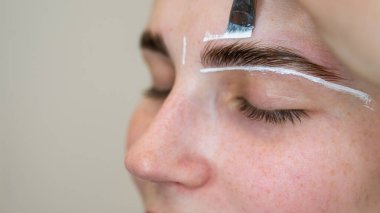 Üstat boyamadan önce beyaz boyayla kaşların şeklini çizer.