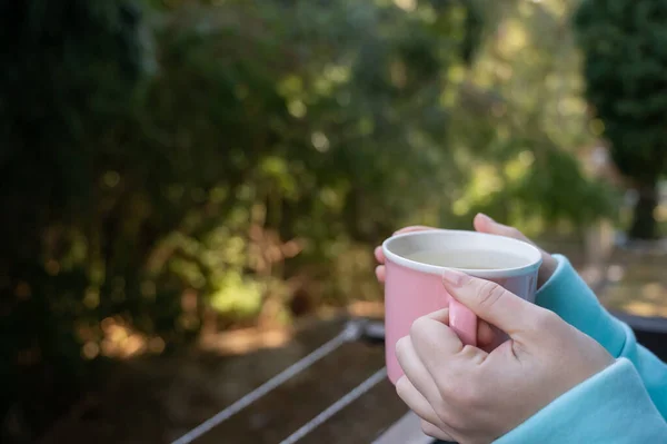 Woman drinking hot drink standing on the balcony