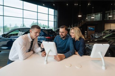 Kafkasyalı evli çift dijital tabletlerden bir araba galerisi seçiyor.